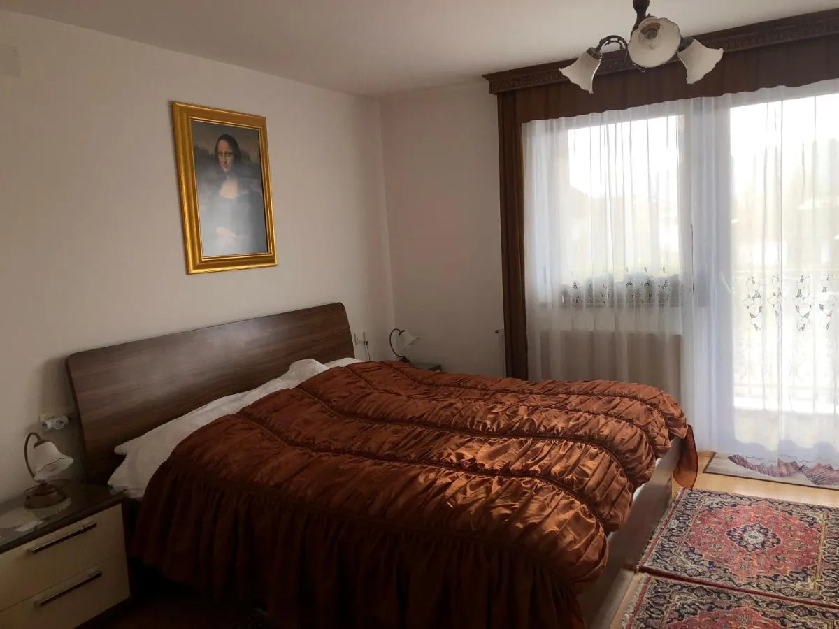Soba z zakonsko posteljo, čipkastimi zavesami in vrati na balkon